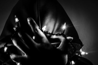 Midsection of woman holding illuminated lighting equipment against sky