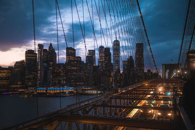 Illuminated bridge over river against sky at night