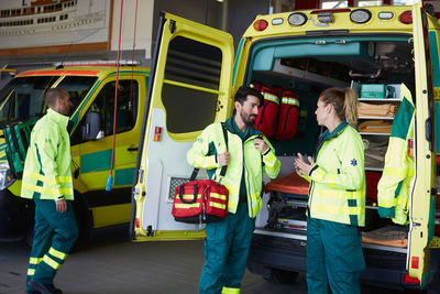 Male paramedic talking to female coworker while standing by ambulance in parking lot