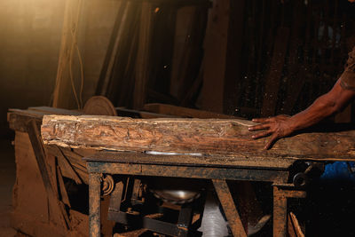 Close-up of a carpenter using a circular saw or a tool to cut wooden planks to make furniture  