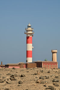 Lighthouse by sea against clear sky