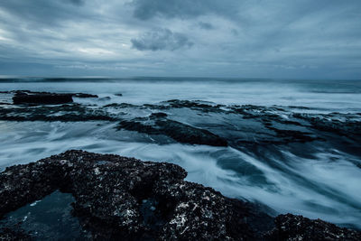 Scenic view of beach against cloudy sky