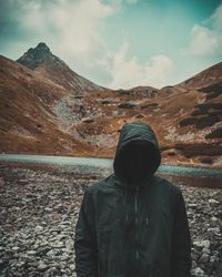 Rear view of man standing on mountain against sky