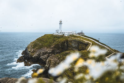 Lighthouse by sea against sky