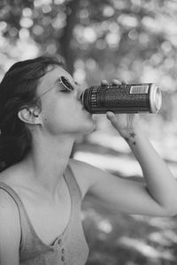 Close-up of young woman drinking soft drink sitting outdoors