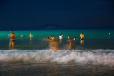 People swimming in sea against sky