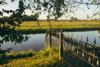 Scenic view of lake by field against sky