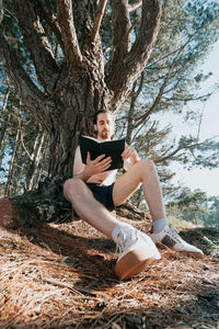 Man reading book against tree