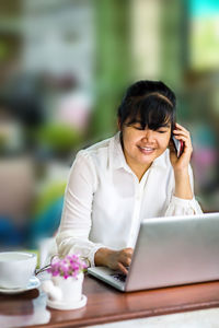 Young woman using mobile phone on table