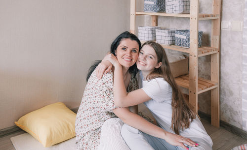 Portrait of mother and daughter embracing at home