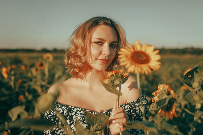 Portrait of smiling young woman holding yellow flower