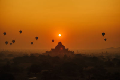 Silhouette of hot air balloons against sky during sunset