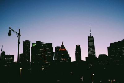 Illuminated buildings in city against clear sky