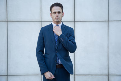 Portrait of businessman standing against wall