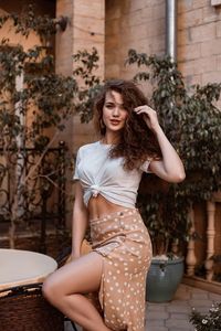 Portrait of young woman standing against building