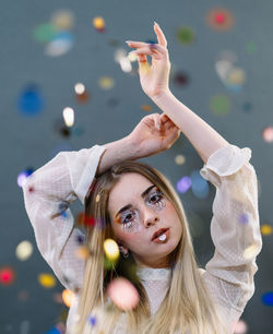 Portrait of young woman with arms raised