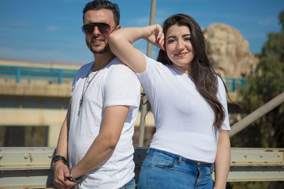 Portrait of smiling young couple standing against sky