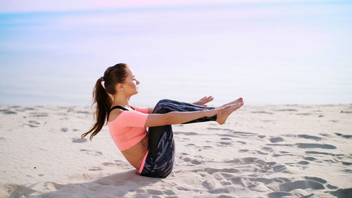 Side view of young woman sitting at beach