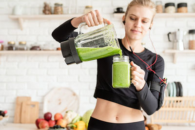 Woman listening music while pouring drink in mason jar