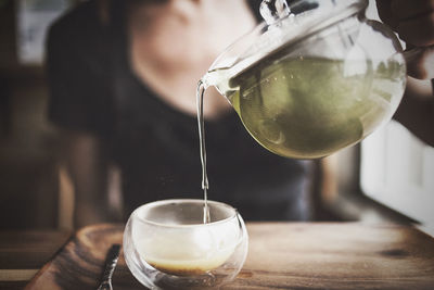 Close-up of woman pouring drink in glass