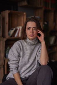 Portrait of woman sitting against shelf