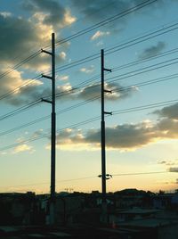 Low angle view of electricity pylon against sky during sunset