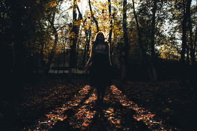 Woman standing against trees in park