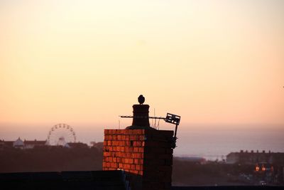 Silhouette man tower against sky during sunset