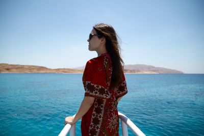 Rear view of young woman standing on yacht bow sailing on red sea