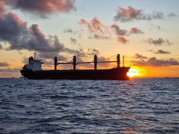 Silhouette boat in sea against sky during sunset