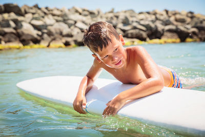 Handsome teenage boy having fun floating on a swim board