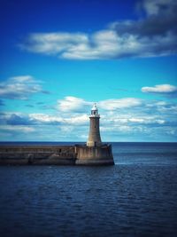 Lighthouse by sea against sky