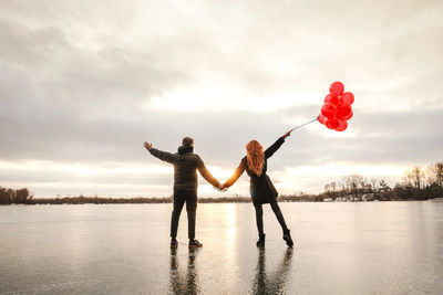 Full length of friends standing on water against sky