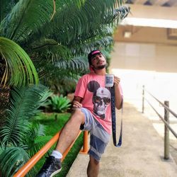 Full length of young man standing against palm trees