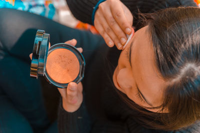 High angle view of woman applying make-up while sitting outdoors