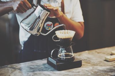 Midsection of man preparing coffee on table