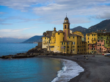 Town by sea against cloudy sky