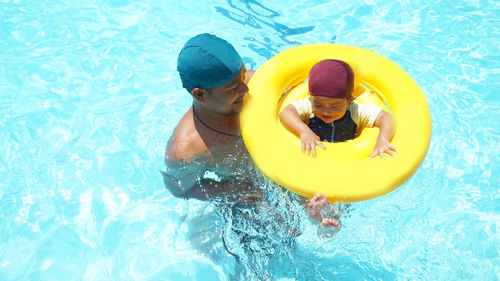 High angle view of father and son swimming in pool