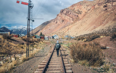 Rear view of people walking on railroad track