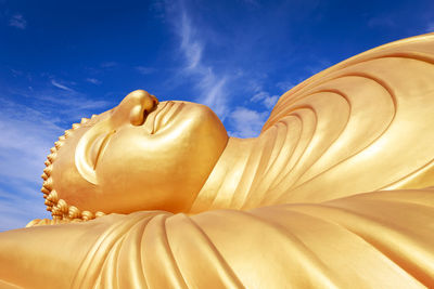 Low angle view of buddha statue against sky