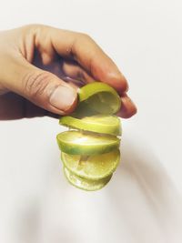 Close-up of hand holding fruit against white background