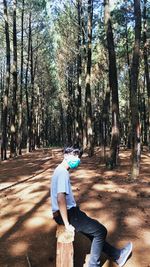 Full length of man wearing mask sitting in forest