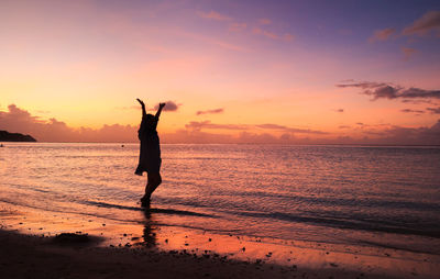 Silhouette man standing on beach against sky during sunset