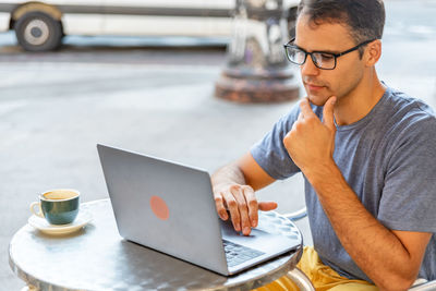 Midsection of man using mobile phone while sitting on table