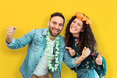 Portrait of smiling young woman using mobile phone against yellow background