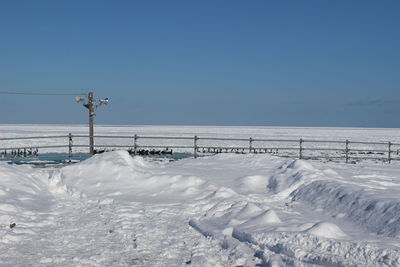 Snow covered land against clear sky