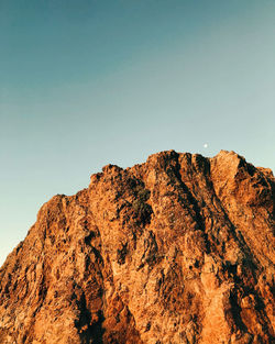 Low angle view of rocky mountains against clear sky