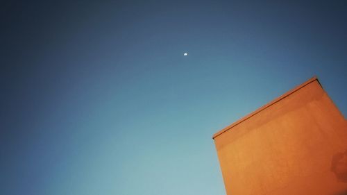 Low angle view of moon against clear blue sky