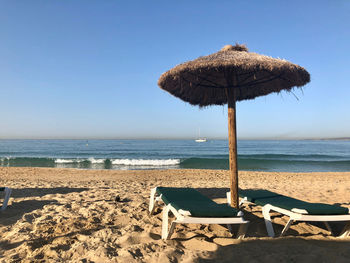 Thatched roof on beach against clear sky