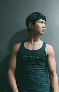 Portrait of young man looking away against wall